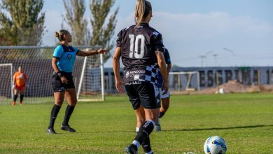 Jogadoras disputam uma partida de futebol feminino ao ar livre em um estádio.