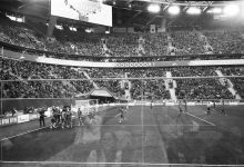 Jogadores de futebol se abraçam e se parabenizam após uma vitória em um estádio lotado.