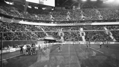 Jogadores de futebol se abraçam e se parabenizam após uma vitória em um estádio lotado.