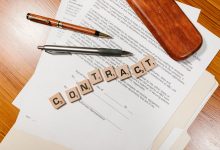 Documentos contratuais em close-up sobre uma mesa, com peças formando a palavra “CONTRACT”.