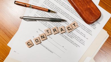 Documentos contratuais em close-up sobre uma mesa, com peças formando a palavra “CONTRACT”.