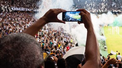 Torcedores registram com um smartphone a atmosfera de uma partida de futebol nas arquibancadas.